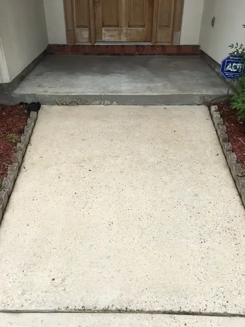 Freshly cleaned concrete entry walk with brick edging leading to a front door
